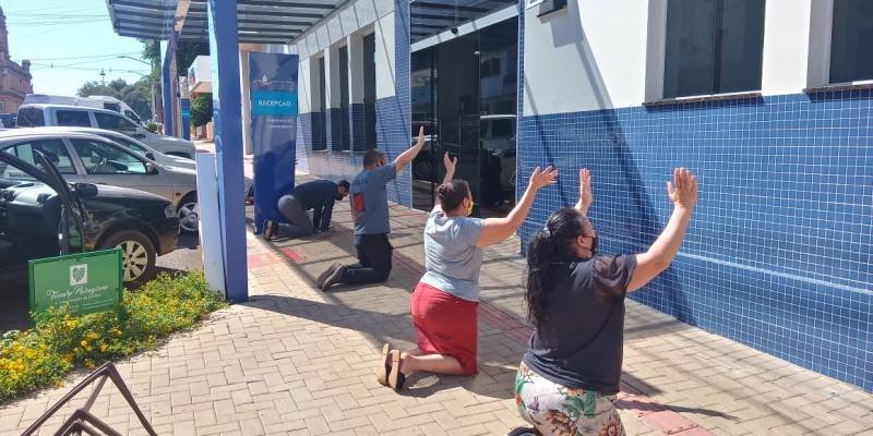 Membros de igreja fazem oração de joelhos em frente ao Hospital Santo Ângelo